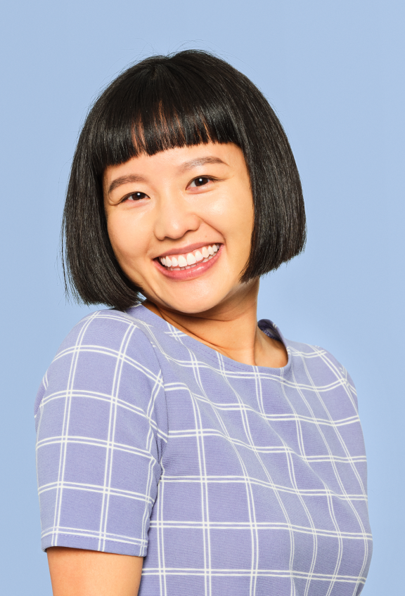 A woman with short black hair wearing a blue shirt, smiling and looking confidently at the camera.