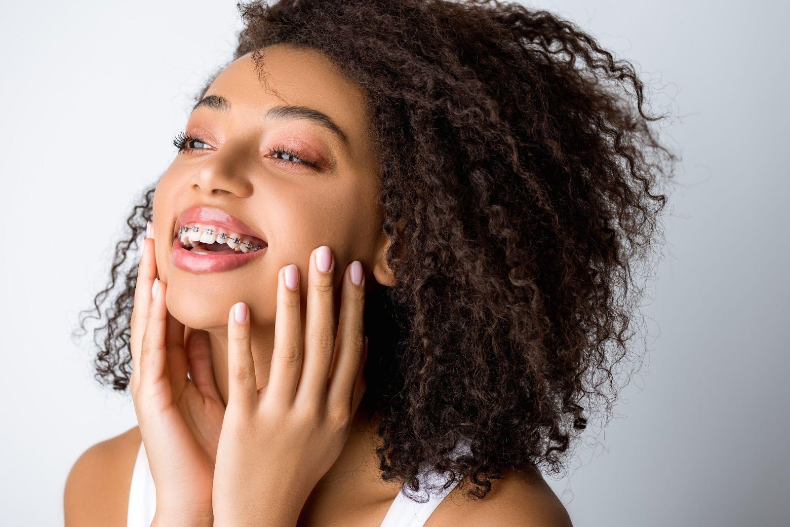 A smiling woman with curly hair showcases her cheerful demeanor, exuding warmth and happiness