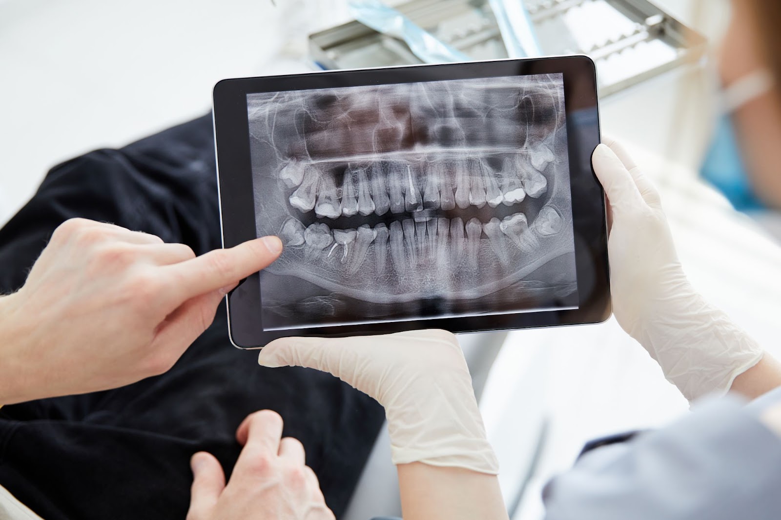 An individual is viewing a dental X-ray on an iPad, highlighting the details of teeth and oral health