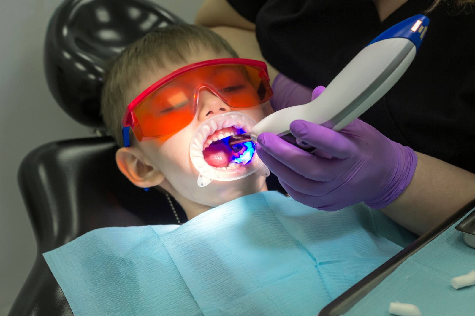 A child receiving dental care from a dentist, showcasing both traditional and laser dentistry techniques.