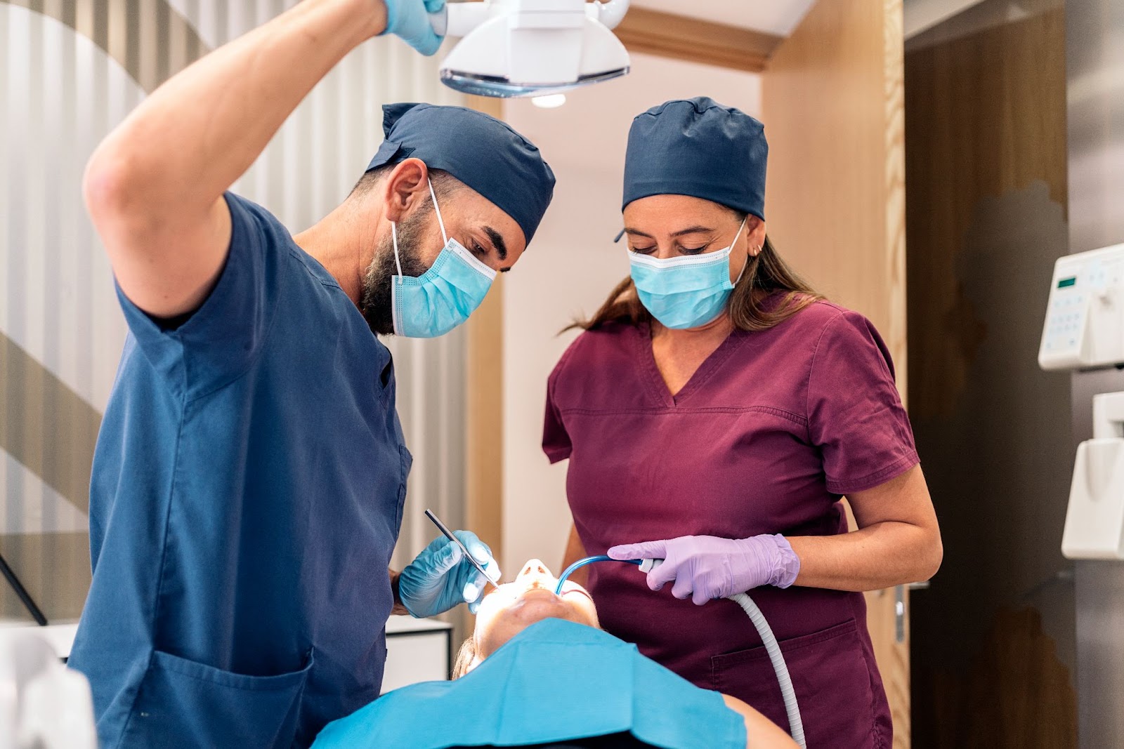 A dentist and assistant apply dental sealants to a patient to prevent tooth decay and cavities during a routine check-up.