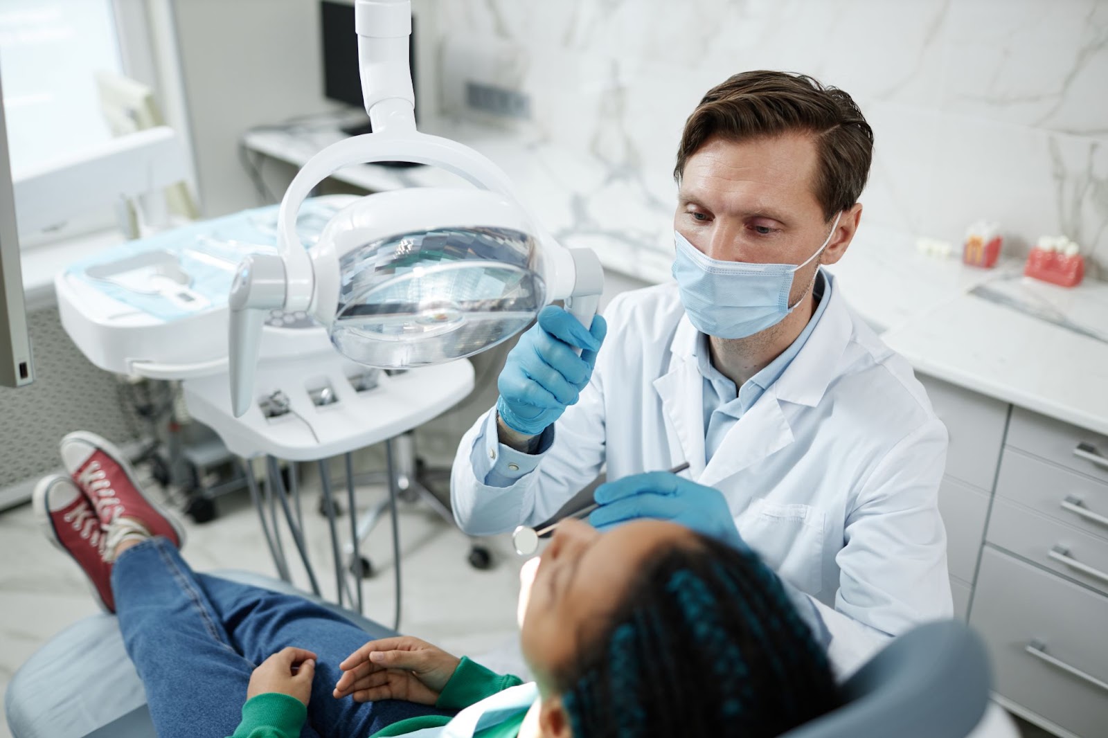 A dentist discusses dental sealants with a patient in a dental chair, focusing on preventing tooth decay and cavities.