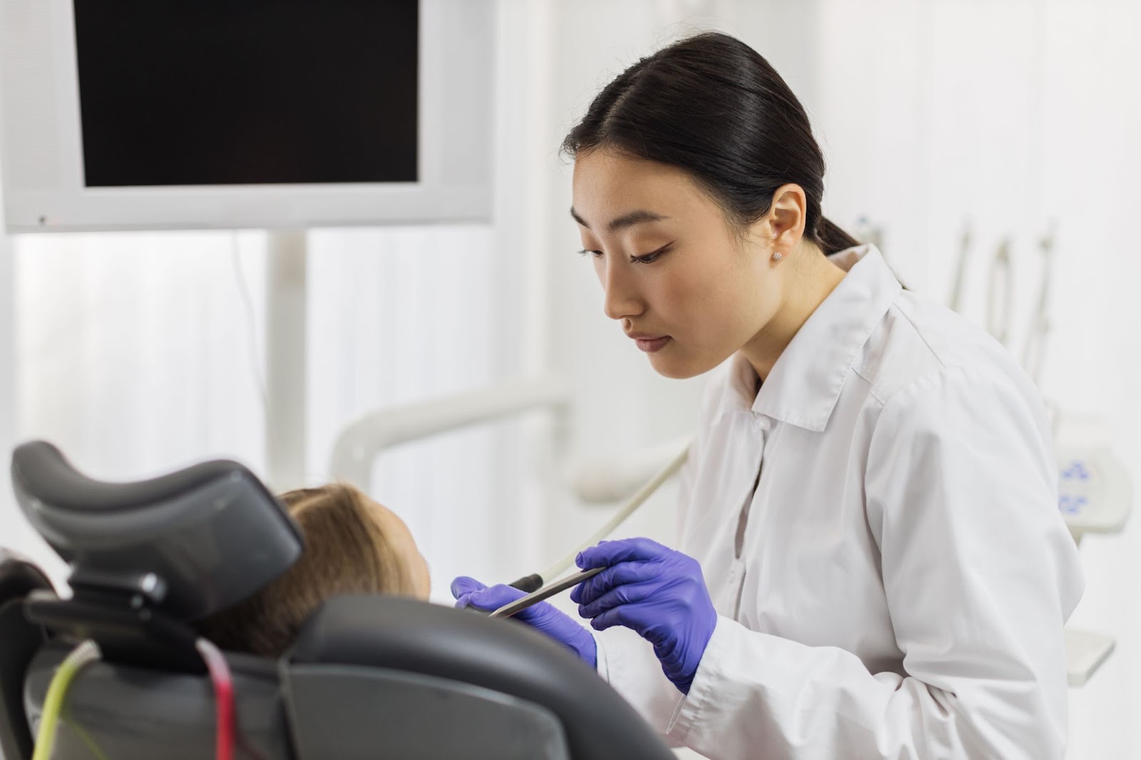 A woman in a dental chair receives a check-up for tooth decay and cavities, with a focus on dental sealants.